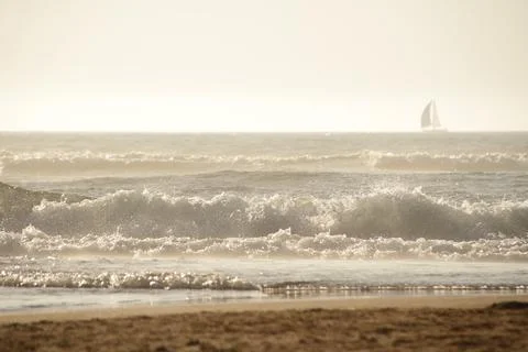 Ocean waves under the sunset with shape of sailboat on the horison Stock-Fotos