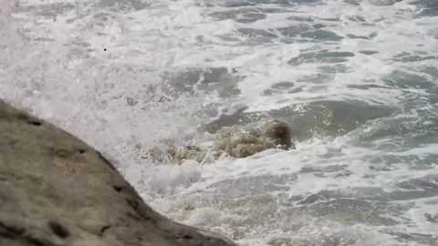 Ocean waves wash over dark rocks Stock Footage 329545620