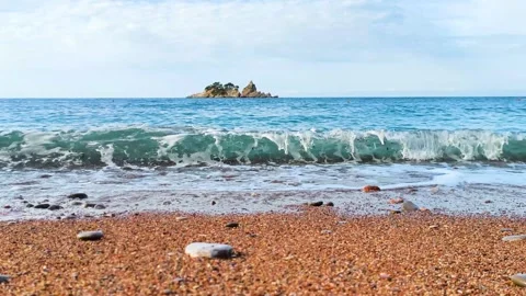 Ocean waves washing over beach with rocky island in distance Stock Footage 340533277