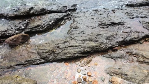 Ocean Waves Washing Over Coastal Rock Formations and Pebbles 動画素材 346737905