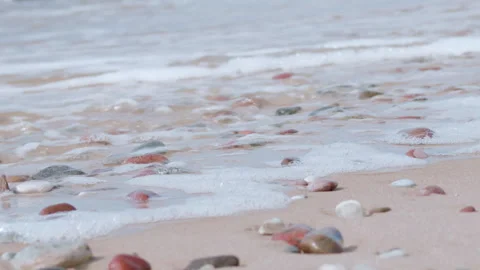 Ocean waves washing over pebbles on a sandy beach 動画素材 346487026