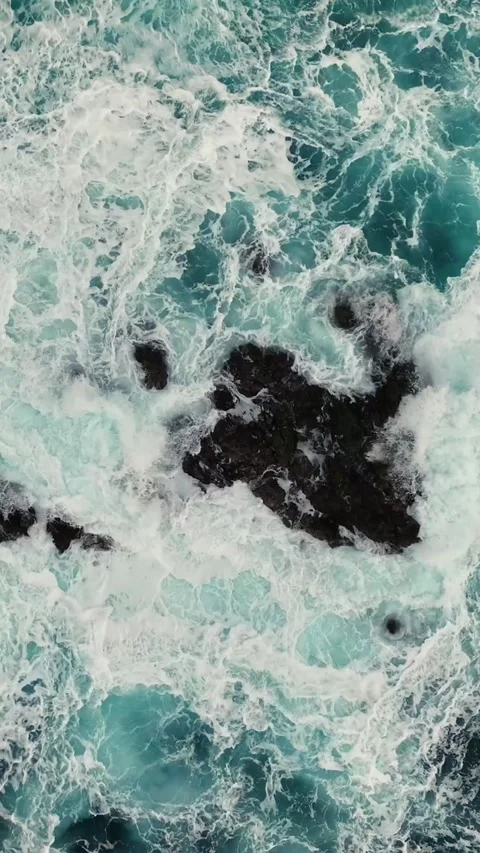 Ocean waves with white foam breaking on the rocks. Aerial top down shot of Stock Footage 270944868