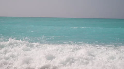 Ocean waves with white foam gently washing over a calm pebble beach Stock Footage 331162838