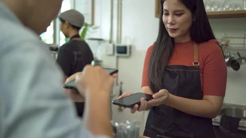Offee shop owners accept payments from customers by paying via smartphone Stock Footage 171358412