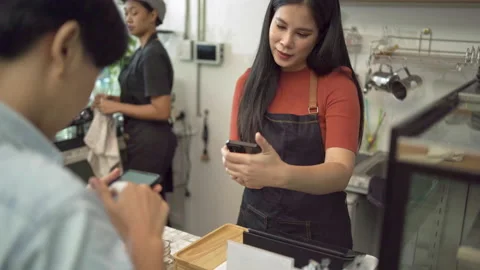 Offee shop owners accept payments from customers by paying via smartphone Stock Footage 171358605