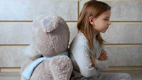 Offended child and bear sit back to back on the floor. Stock Footage 261003771