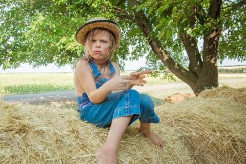 Offended child sits on a haystack Stock Photos