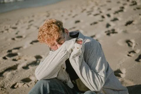 Offended guy looks frowningly at the camera, covers half his face with his ha Stock Photos