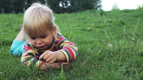 An offended sad child lies on the grass and tells something Stock Footage 135035448