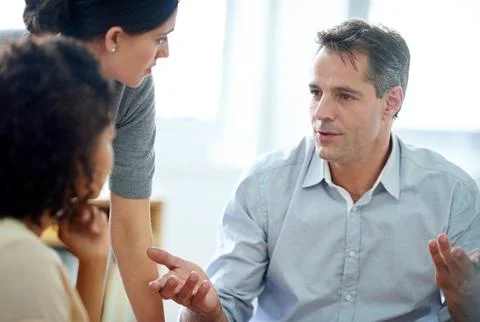 Offering a few experienced pointers. a group of coworkers having a discussion in Stock Photos
