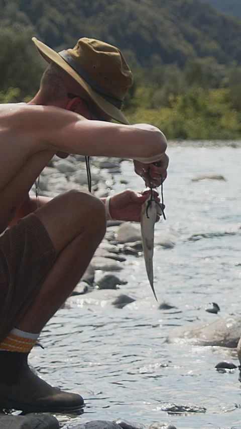 Offgrid man cleaning salmon on river in the mountains. Primitive life. A Stock Footage 272992268