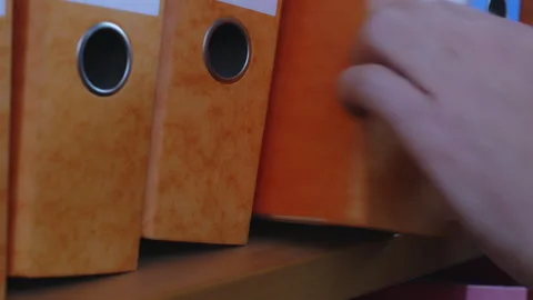 Office Admin Clerk Selecting and Replacing Archive Binder on Filing Shelf Close Stock Footage 339082625