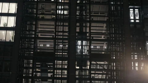 Office building in evening, glass elevators moving behind illuminated windows Stock Footage 323973046