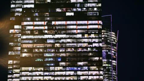 Office building in the evening with lightened workspaces. Stock Photos