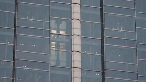Office building with glass elevators moving up down behind illuminated windows Stock Footage 323973007