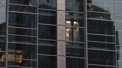 Office building with glass elevators moving up down behind illuminated windows Stock Footage 323973008
