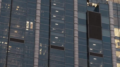 Office building with glass elevators moving up down behind illuminated windows Stock Footage 323973016