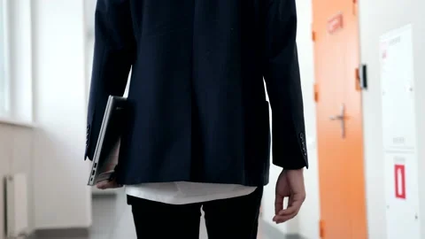 Office building inside. A guy in a jacket walks along the corridor holding Stockbeeldmateriaal 162192692