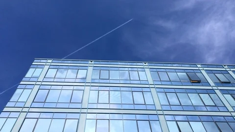 Office building windows reflecting blue sky and flying plane Stock Footage 104208102