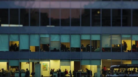 Office building windows showing employees working late at dusk Vídeos de archivo 344814702