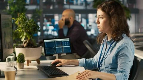 Office clerk at computer desk reading documentation files, solving tasks Foto stock