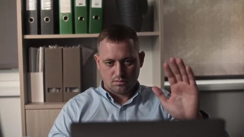 An office clerk waves hello during a video conference at a laptop in the office Stock Footage 307597968