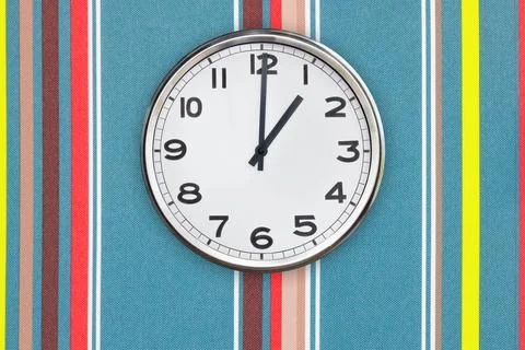 Office clock showing one o'clock on a colorful wall Stock Photos