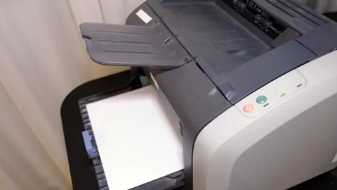 Office closeup shows a desktop printer ready to output documents, sheet sliding Video stock 330077160