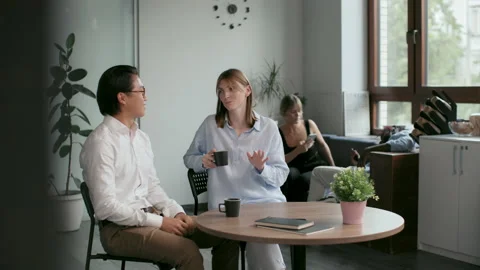 Office co-workers with mugs talk at meeting room. Friendly teamwork of asian man Stock-Footage 199485348