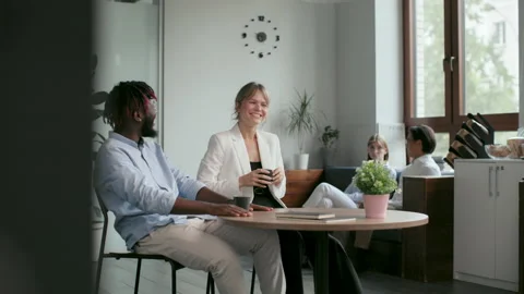 Office co-workers with mugs talk at meeting room. Friendly teamwork of black man Видео 199485570