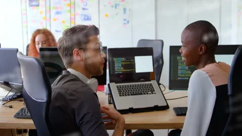 In office, colleagues discussing code on laptops with digital animation overlay Stock Footage 303429394