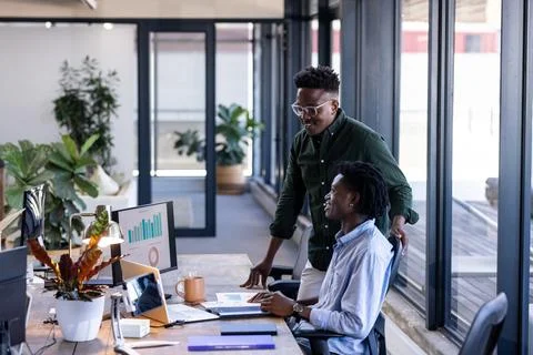 In office, colleagues discussing data on computer screen, collaborating and Fotos de archivo