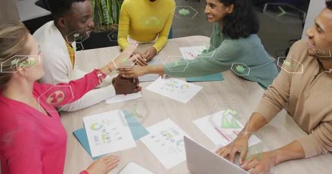 Office colleagues stacking hands smiling in meeting room with printed charts  스톡 사진