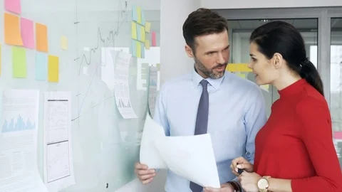Office colleagues working on whiteboard planning new business Stock Footage 73671931