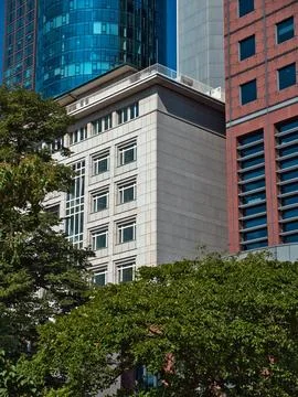 Office complex with glass front under a clear sky with trees in the foregroun Stock-Fotos