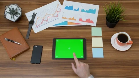Office desk and tablet computer with green screen and hands taping on it. Stock Footage 87569565