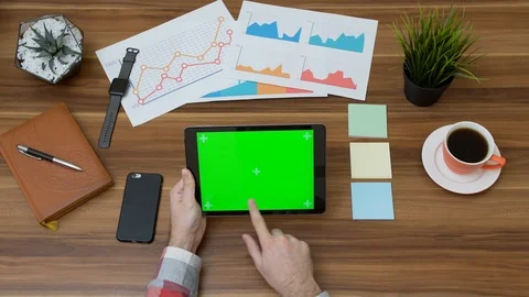 Office desk and tablet computer with green screen and hands scrolling on it. Stock Footage 87569579