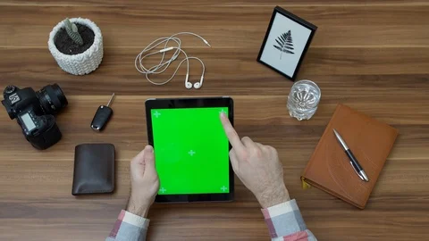 Office desk and tablet computer with green screen and male scrolling on it. Stock Footage 87569927
