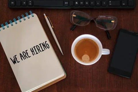 Office desk with computer, coffee cup, smartphone, glasses and We are hiring  Stock Photos