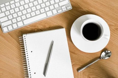 Office desk with notepad, computer keyboard and coffee cup. View from above Stock Photos