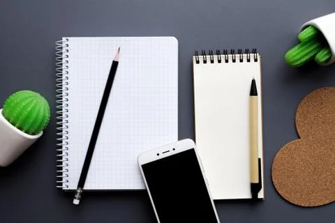 Office desk table with blank notepad, smartphone, stationery and cacti Stock Photos