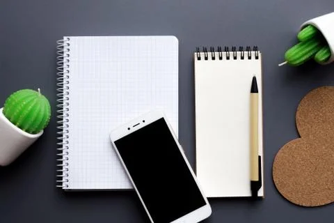 Office desk table with blank notepad, smartphone, stationery and cacti Stock Photos