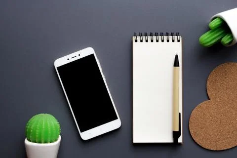 Office desk table with blank notepad, smartphone, stationery and cacti Stock Photos