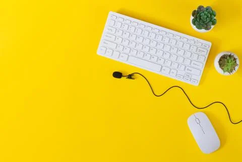 Office desk table with keyboard, mouse, microphone and plants top view on yel Stock Photos