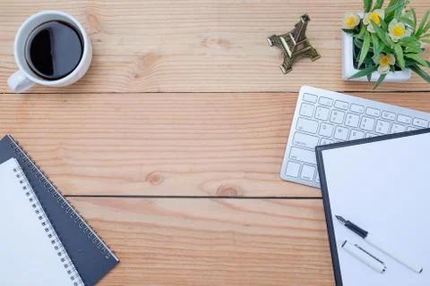 Office desk table with keyboard, notebook, pen, cup of coffee and flower. Top Stock-Fotos