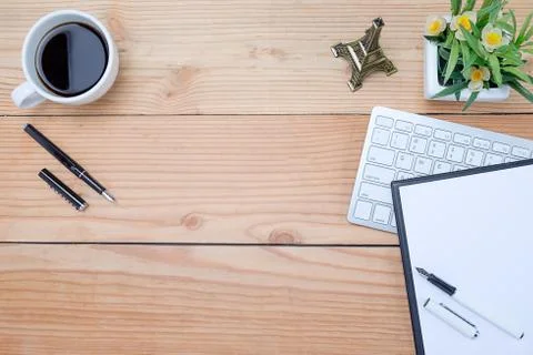 Office desk table with keyboard, notebook, pen, cup of coffee and flower. Top Stock-Fotos