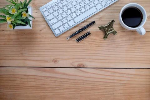 Office desk table with keyboard, notebook, pen, cup of coffee and flower. Top Stock-Fotos