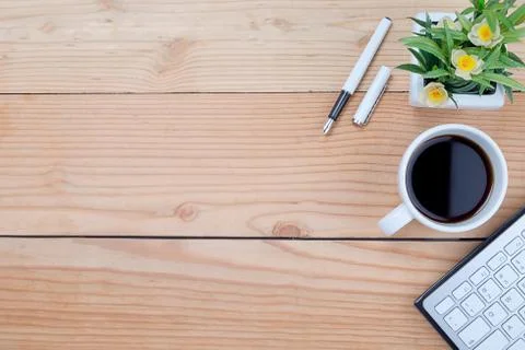 Office desk table with keyboard, notebook, pen, cup of coffee and flower. Top Stock-Fotos