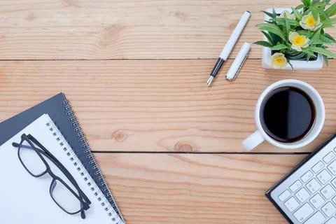 Office desk table with keyboard, notebook, pen, cup of coffee and flower. Top 스톡 사진
