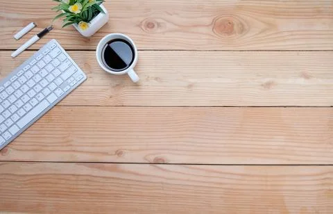 Office desk table with keyboard, notebook, pen, cup of coffee and flower. Top Stock-Fotos